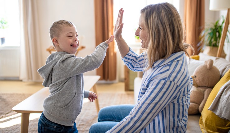 Eine Frau spielt mit einem kleinen Jungen mit besonderen Bedürfnissen.